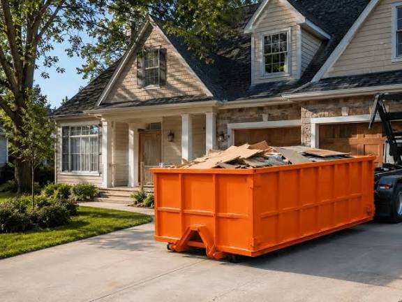 Orange roll-off dumpster with renovation debris in a residential driveway in Jackpot, NV